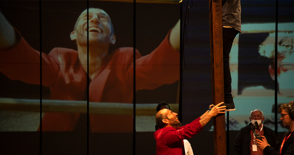 Un homme habillé en rouge tient une échelle sur laquelle un homme est en équilibre